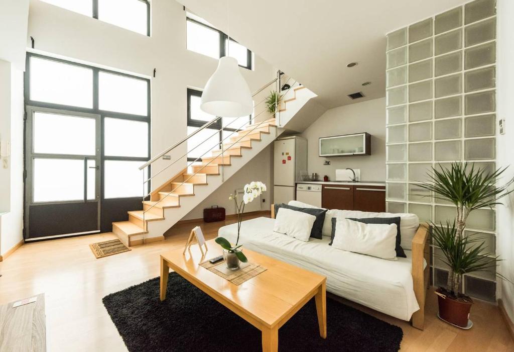 sala de estar con sofá blanco y escaleras en El loft de San Juan en Madrid