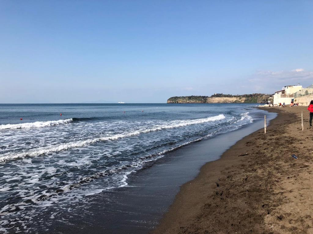 a beach with people walking on the sand and the water at Casa Cucurullo in Procida