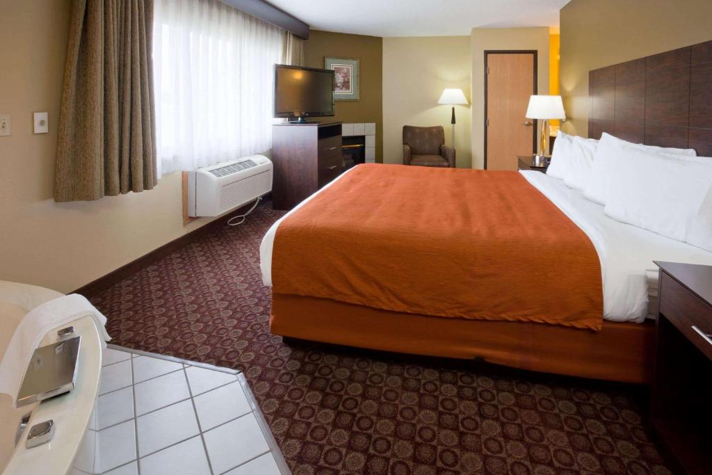 a hotel room with a large bed and a television at AmericInn by Wyndham Blue Earth in Blue Earth