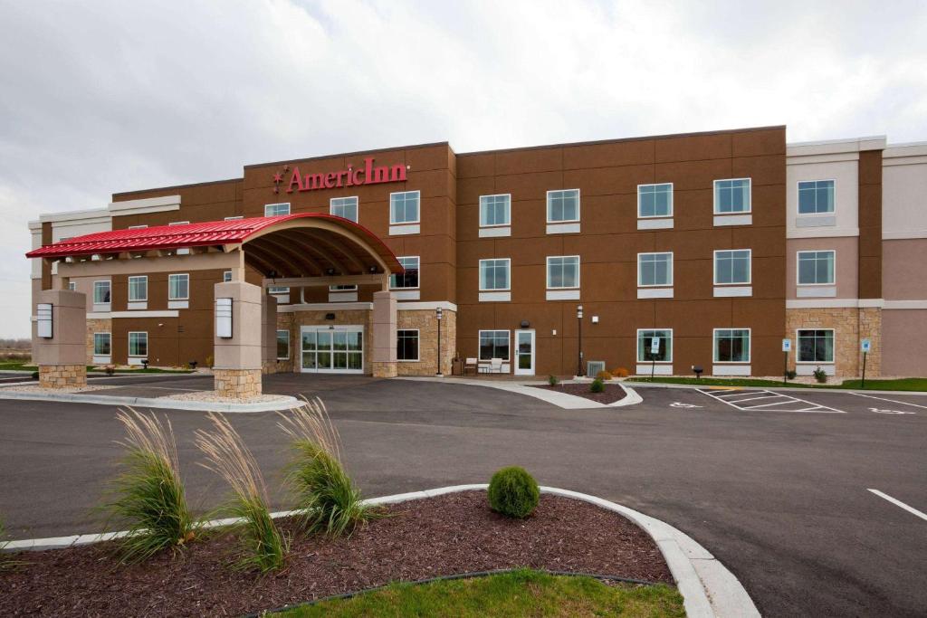 a front view of a hotel with a parking lot at AmericInn by Wyndham Waupun in Waupun