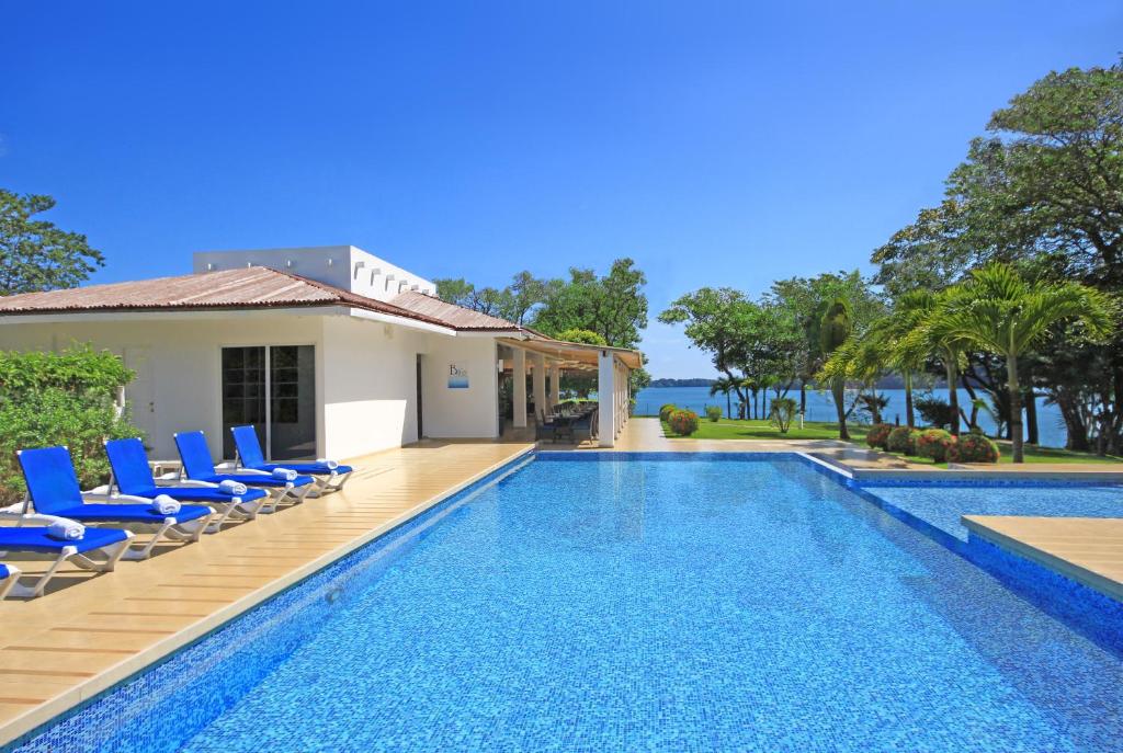 a villa with a swimming pool and blue chairs at Bocas del Mar in Boca Chica