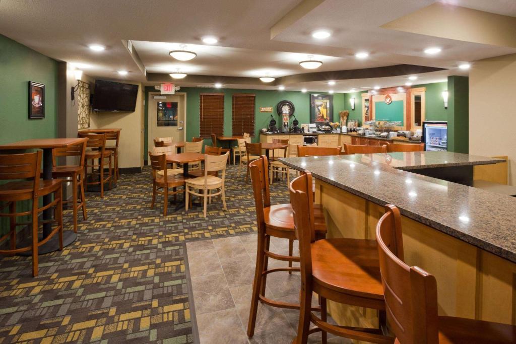 a restaurant with a bar with wooden tables and chairs at AmericInn by Wyndham Hawley in Hawley