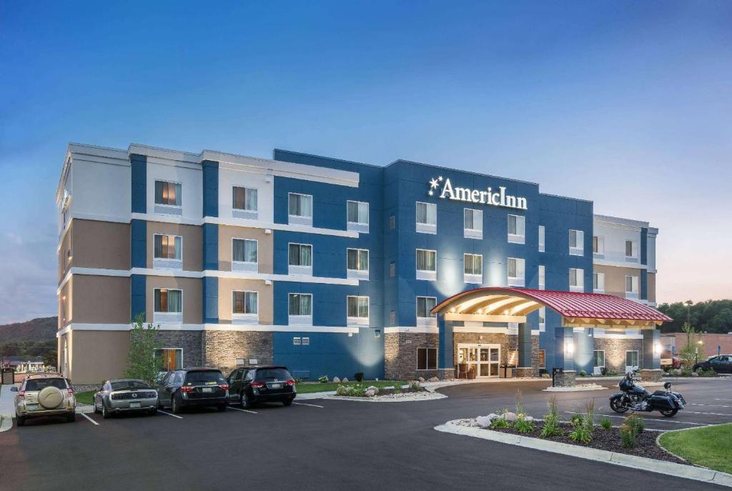 a hotel with cars parked in a parking lot at AmericInn by Wyndham Winona in Winona