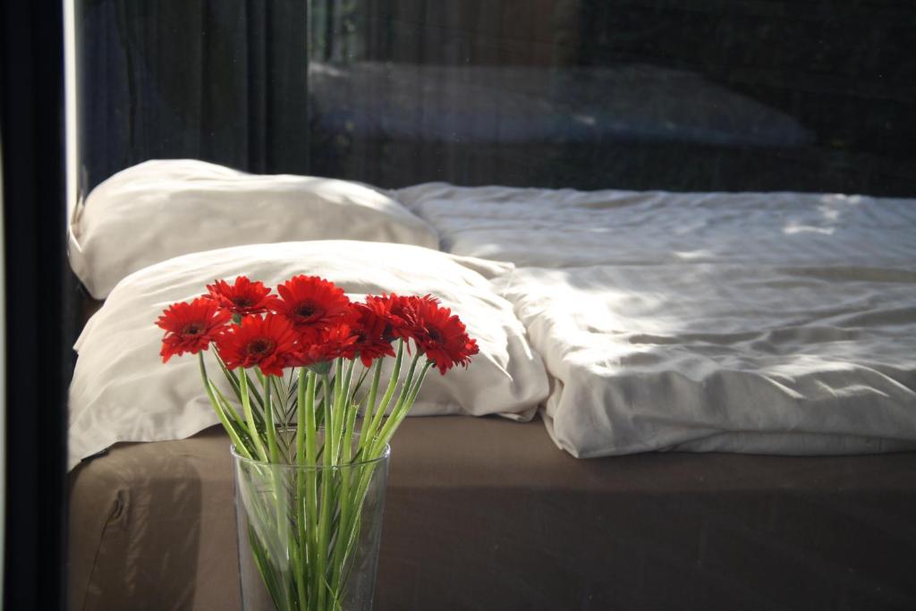イーペルにあるLa Chambre d'Amisのベッド横のテーブルに赤い花瓶