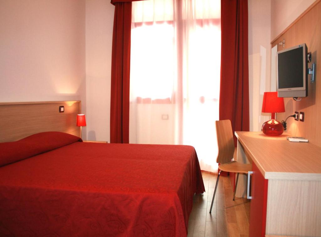 1 dormitorio con cama roja y escritorio con TV en Hotel Residence Key Club, en Montalto di Castro