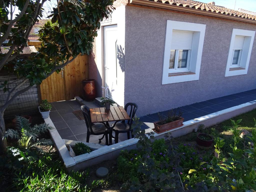 une terrasse avec une table et des chaises devant une maison dans l'établissement rêverie, à Balaruc-les-Bains