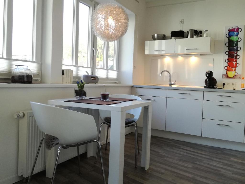 a white kitchen with a white table and chairs at Zimmer zum Hof in Herdecke