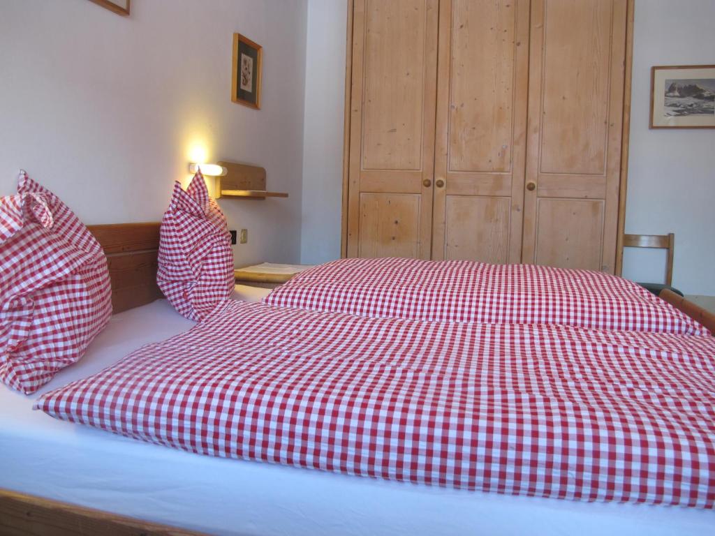 a bed with a red and white checkered blanket at Villa Ula Verda- Apartments Marianna in Santa Cristina in Val Gardena