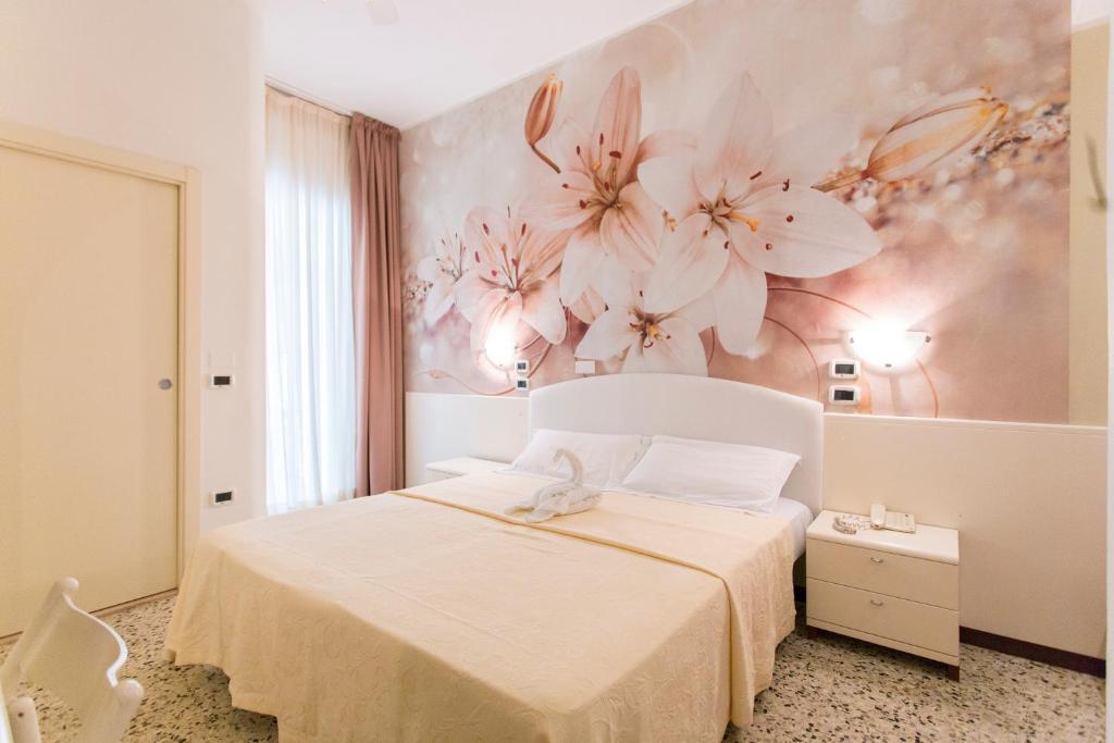 a bedroom with a white bed with flowers on the wall at Sirena Boutique Hotel in Gabicce Mare