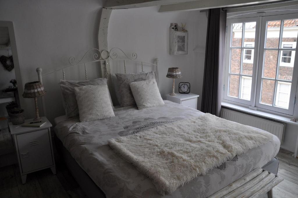 a bedroom with a bed with a white comforter and two windows at De Slapende Leeuw in Middelburg