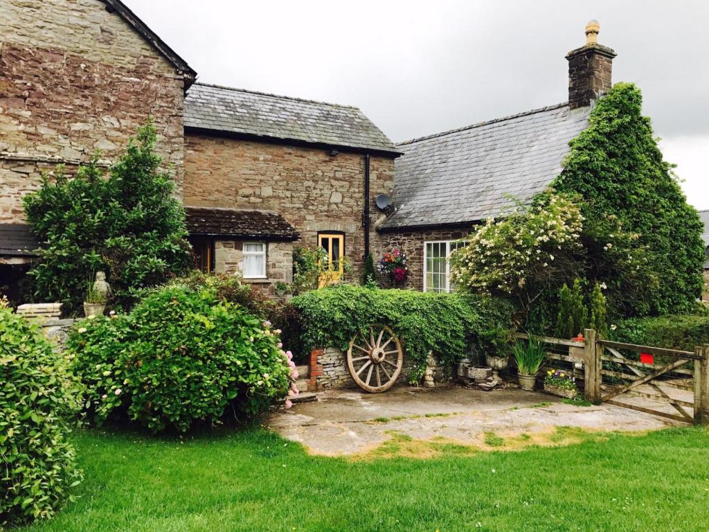 an old stone house with a wooden wheel in front of it at The Draen Bed and Breakfast in Brecon
