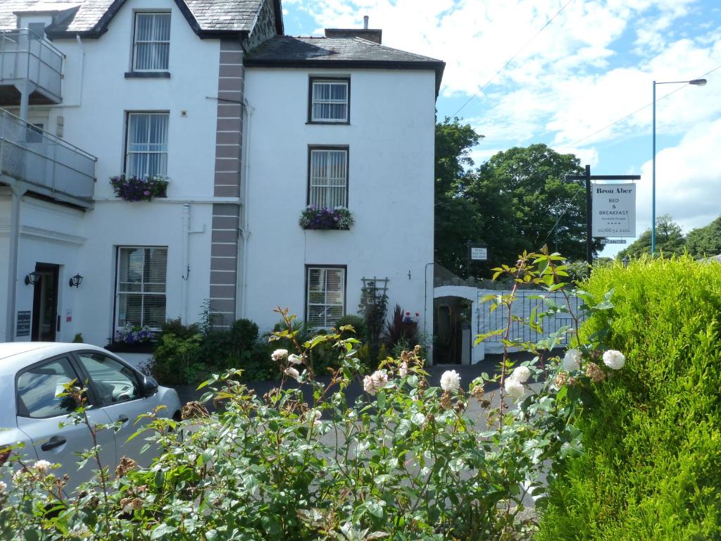 a white house with flowers in front of it at Bron Aber in Criccieth