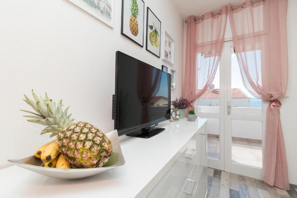 a fruit in a bowl on a desk with a television at Apartman Roko in Petrcane