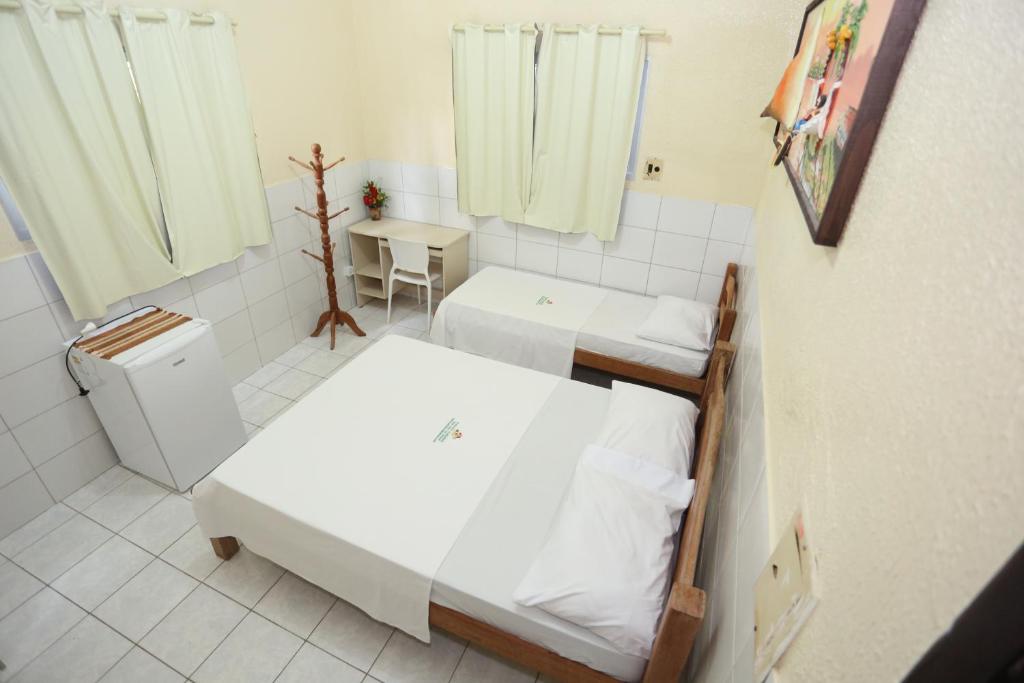 a small room with two beds and a table at Paraíso Olindense in Olinda