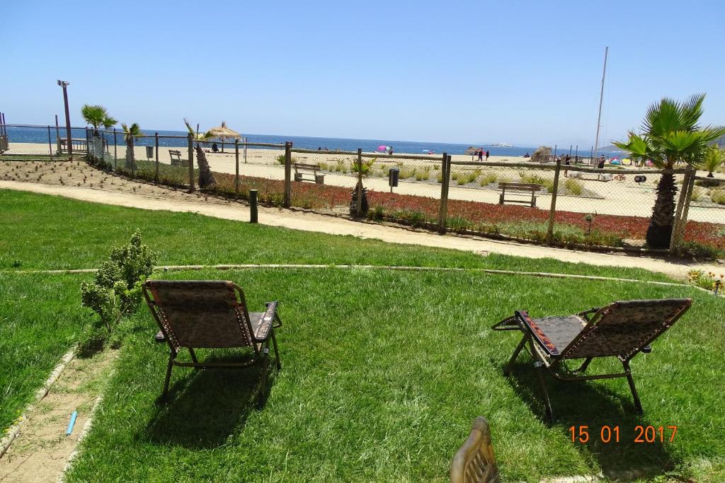 two chairs sitting in the grass near the beach at Departamento 102 Alicante in Papudo