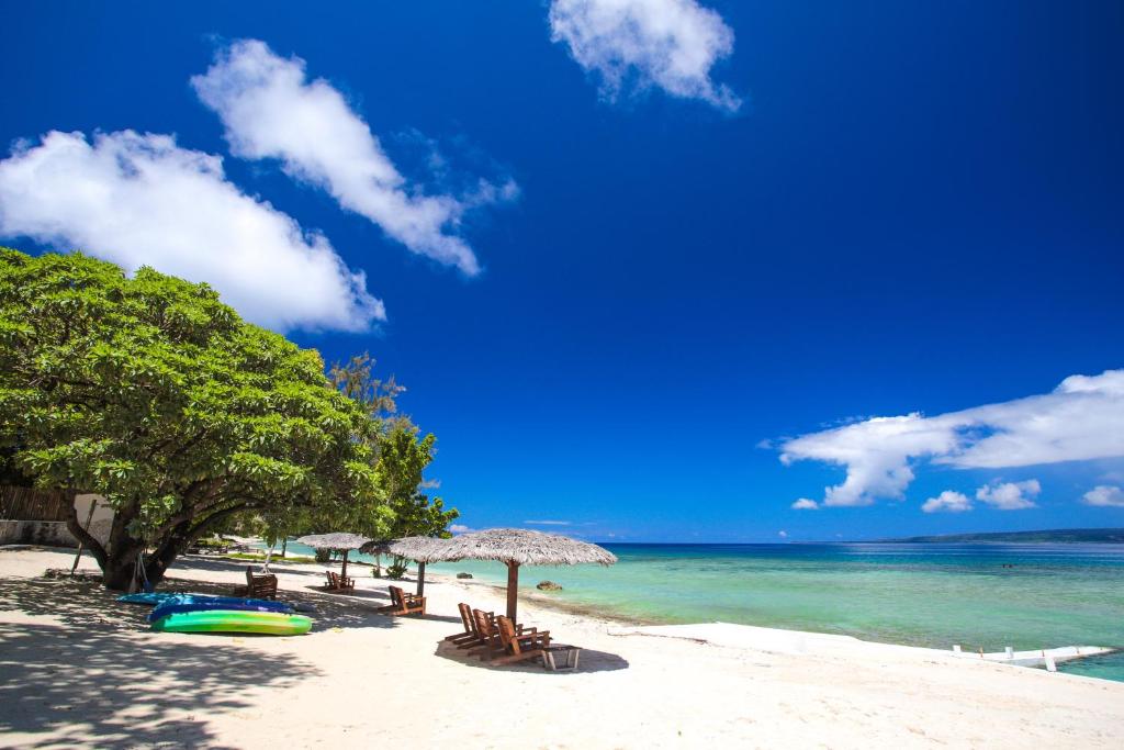 a beach with chairs and umbrellas and the ocean at Coco Beach Resort in Port Vila