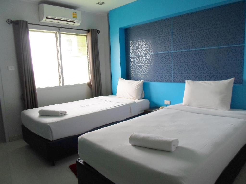 two beds in a room with blue walls at Pongkaew Hotel in Surat Thani