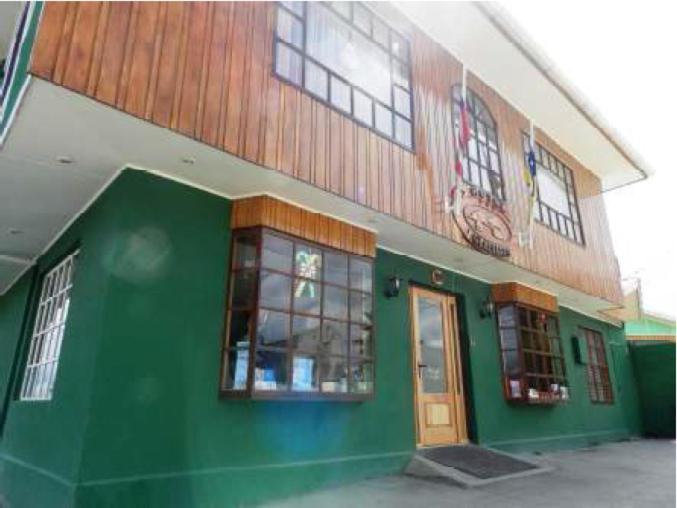 un edificio verde con ventanas y una puerta en Hotel Glaciares en Puerto Natales