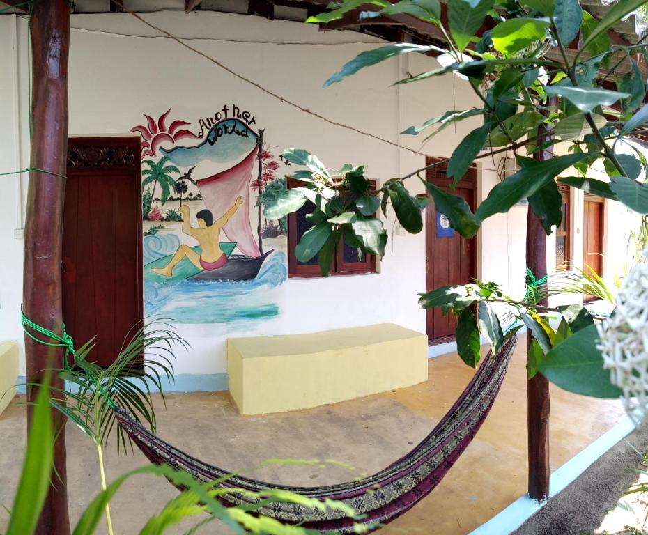 um quarto com uma rede de descanso e uma pintura na parede em Another World em Arugam Bay