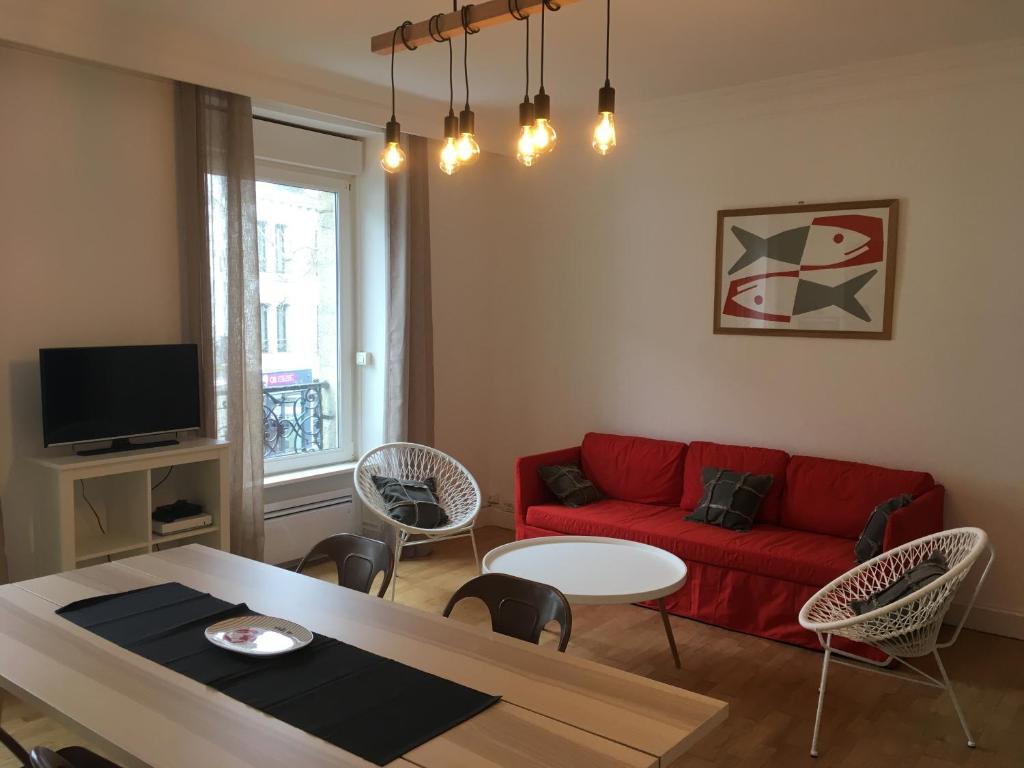 a living room with a red couch and a table at LA VILLE A LA MER N°1 in Concarneau