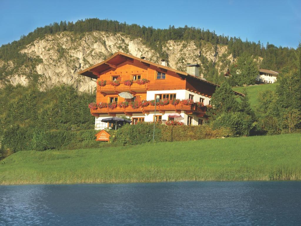 une maison sur une colline à côté d'une masse d'eau dans l'établissement Haus Seeblick am See, à Thiersee