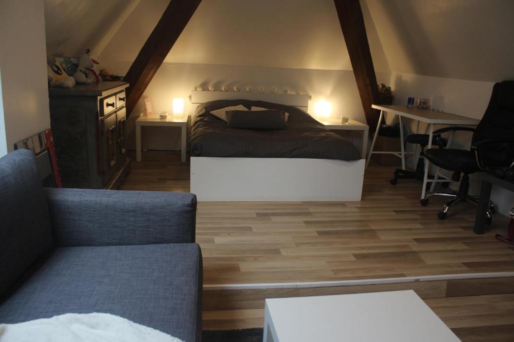 a bedroom with a bed and a couch and a table at Appartement et gîte Chez l'Habitant in Guebwiller