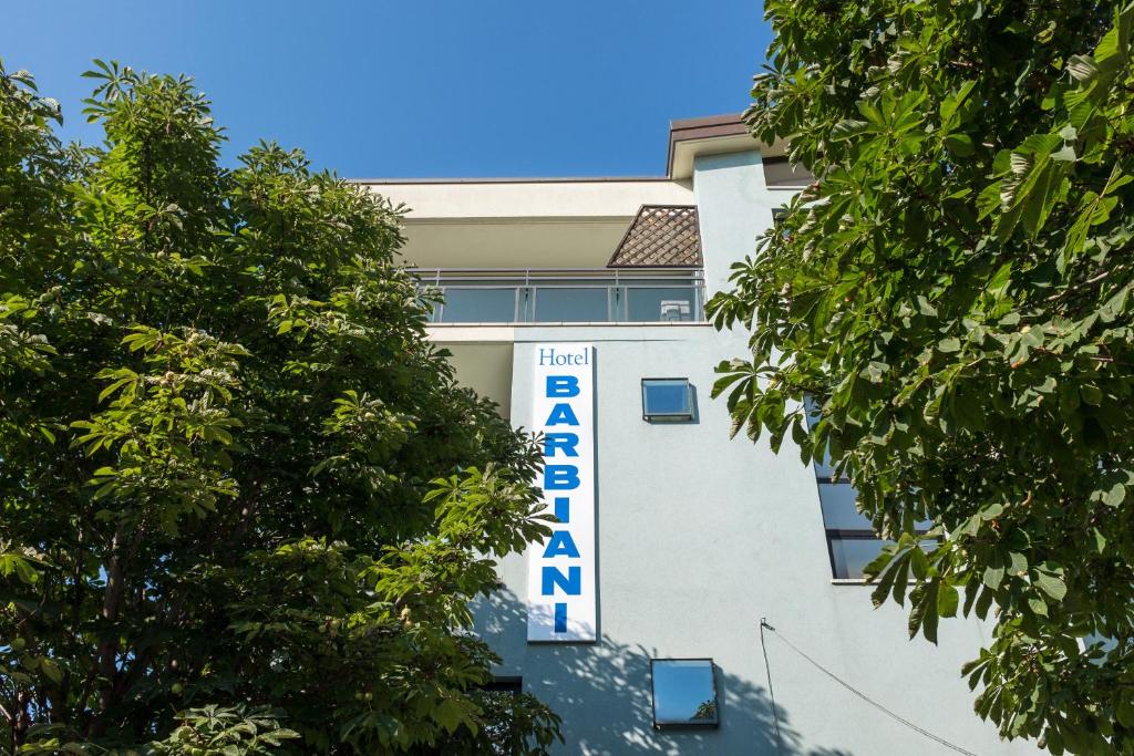 a white building with a blue sign on it at Hotel Barbiani in Rimini