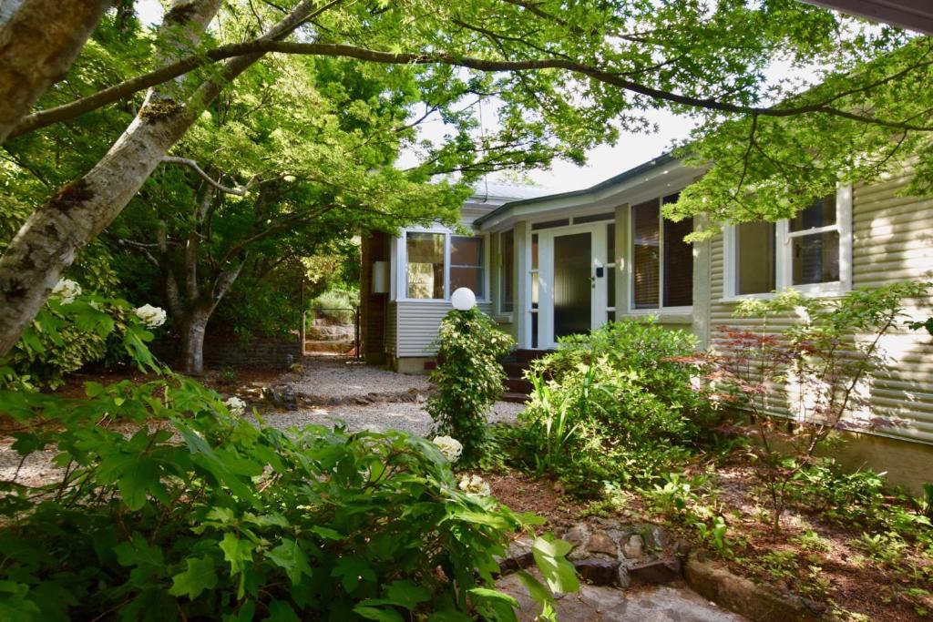 a white house with a porch and trees at Calamandah House of Blackheath in Blackheath