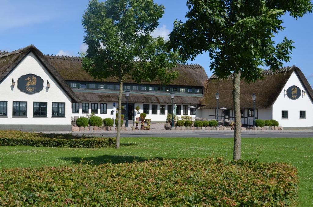 un grand bâtiment blanc avec un toit marron dans l'établissement Munkebo Kro & Hotel, à Munkebo