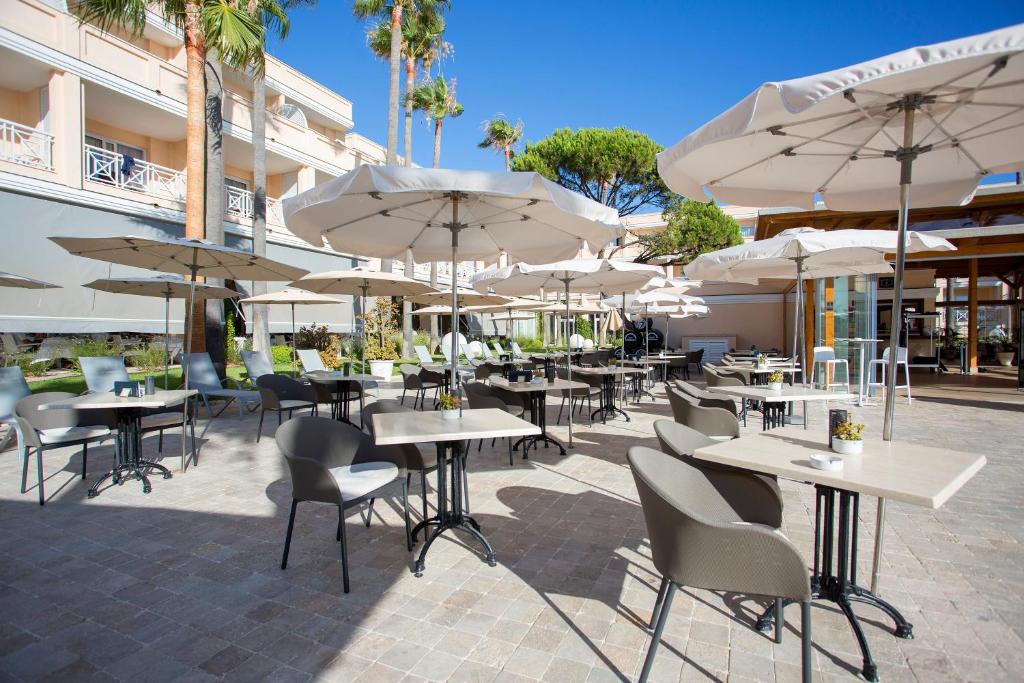 an outdoor patio with tables and chairs with umbrellas at Hipotels Playa La Barrosa - Adults Only in Chiclana de la Frontera