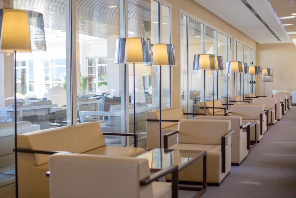 a row of chairs and tables in a room with windows at Hipotels Playa La Barrosa - Adults Only in Chiclana de la Frontera