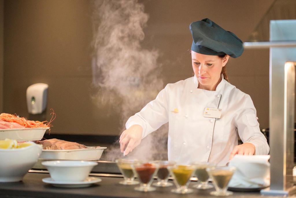 a chef preparing food in a kitchen at Hipotels Playa La Barrosa - Adults Only in Chiclana de la Frontera
