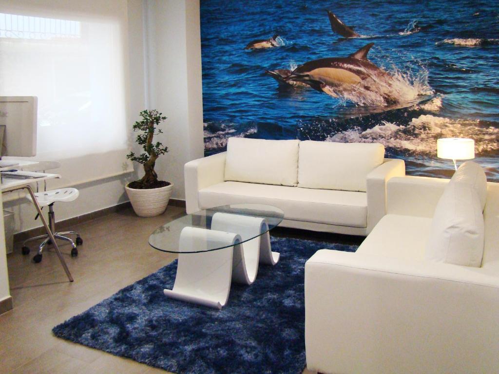 una sala de estar con muebles blancos y una pintura de ballenas en Bekale, en Ea