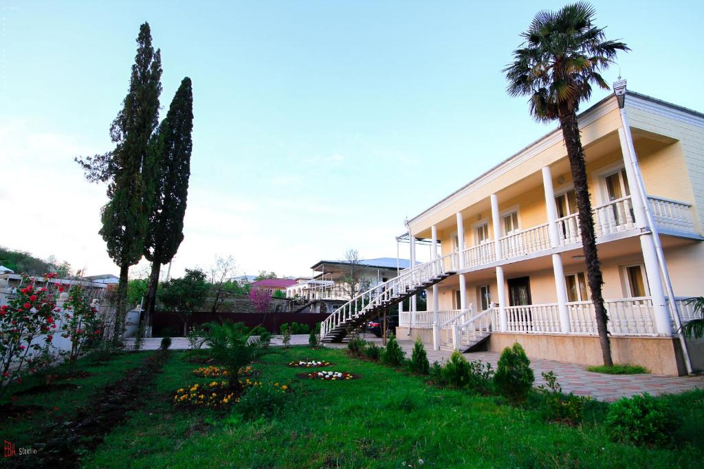 a building with palm trees in front of a yard at Green Garden Guest House in Tskaltubo