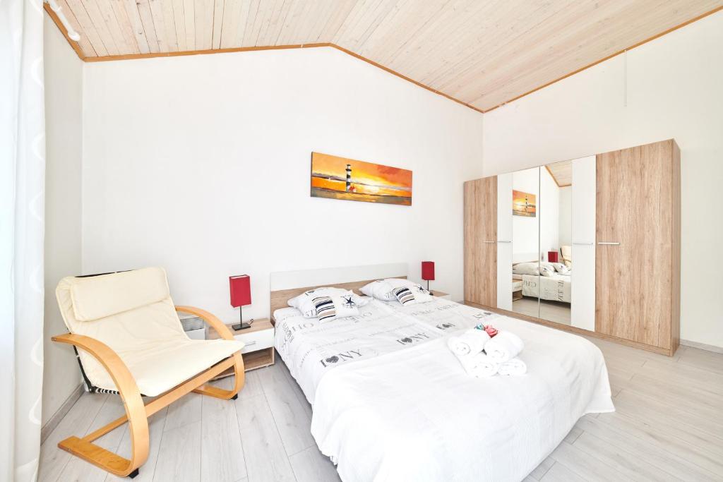 Biały pokój z 2 łóżkami i krzesłem w obiekcie Apartments Gvarda w mieście Umag