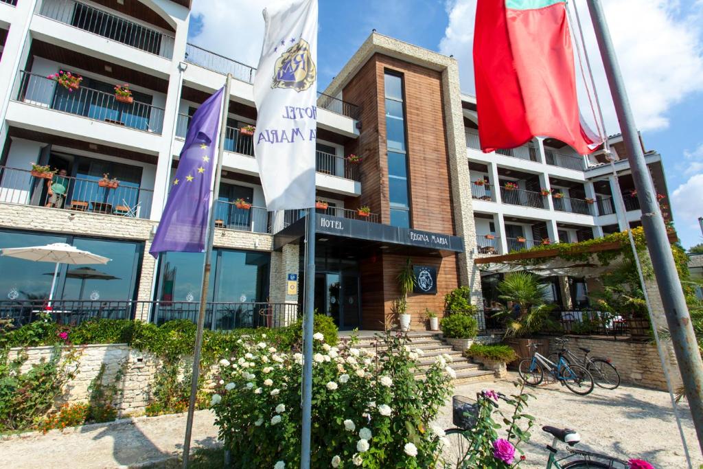 a hotel with flags in front of a building at Regina Maria Spa Design Hotel in Balchik