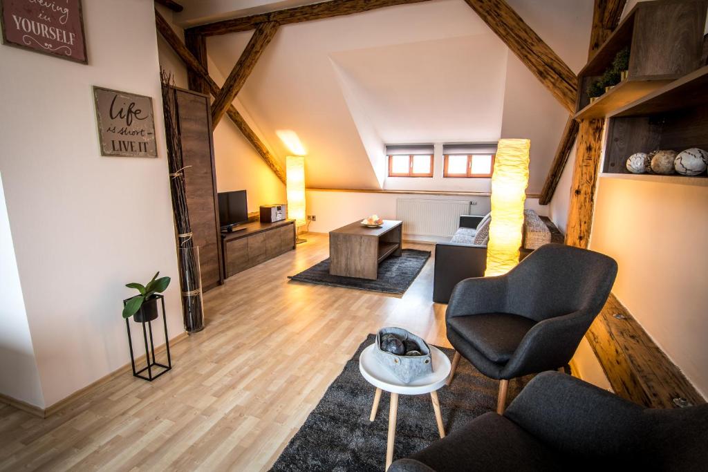ein Wohnzimmer im Dachgeschoss mit einem Sofa und Stühlen in der Unterkunft Tylova Apartments in Kutná Hora