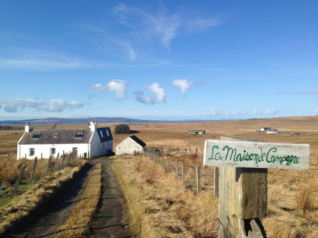 a sign on a fence in a field with a house at La Maison de Campagne in Kilmuir