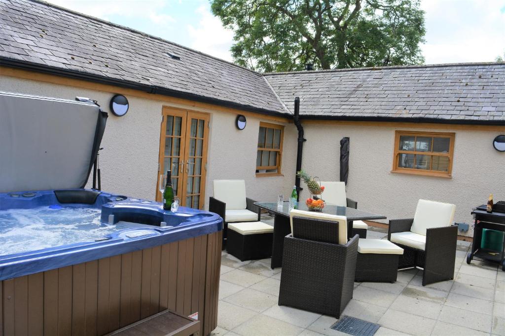 - un bain à remous sur une terrasse avec une table et des chaises dans l'établissement The Cottage, à Benllech