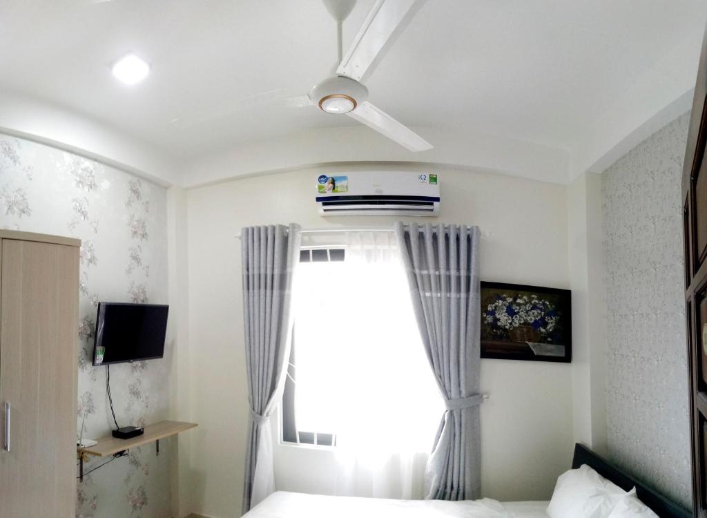 a bedroom with a bed with a ceiling fan and a window at Tin Tin Hue Hostel in Hue