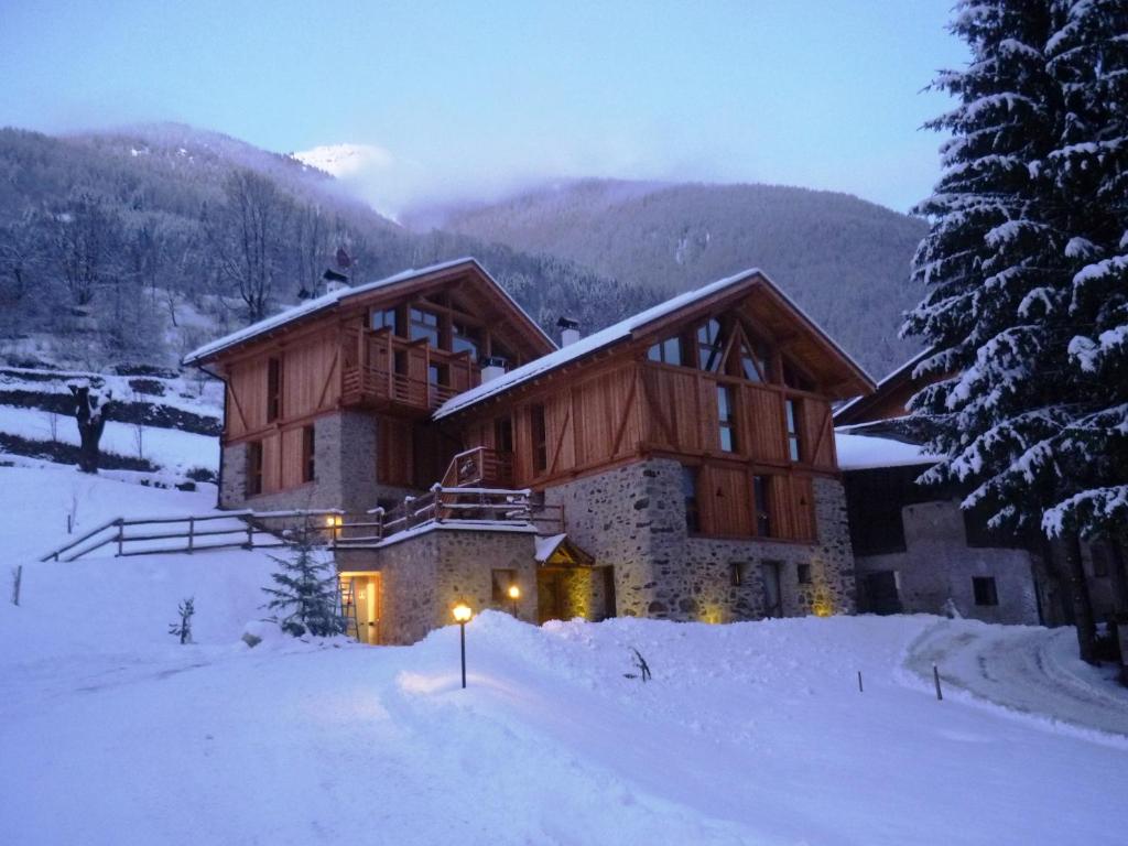 ein großes Holzhaus im Schnee mit Bergen in der Unterkunft Maso Fior di Bosco - Val di Rabbi - Esercizio Rurale in Rabbi