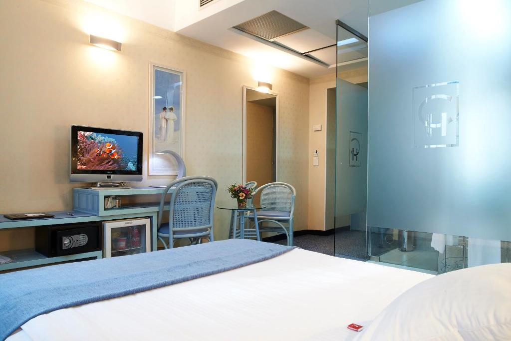 a bedroom with a bed and a tv and chairs at Continental Forum Sibiu in Sibiu