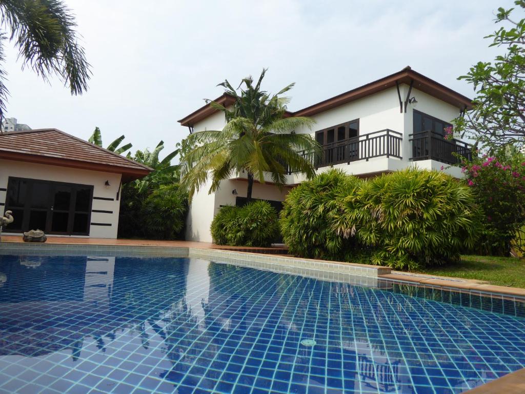 a villa with a swimming pool in front of a house at Tropicana Beach Villa at VIP Resort in Ban Phe