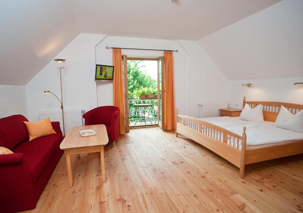 a bedroom with a bed and a red couch at Sporerhof in Murnau am Staffelsee