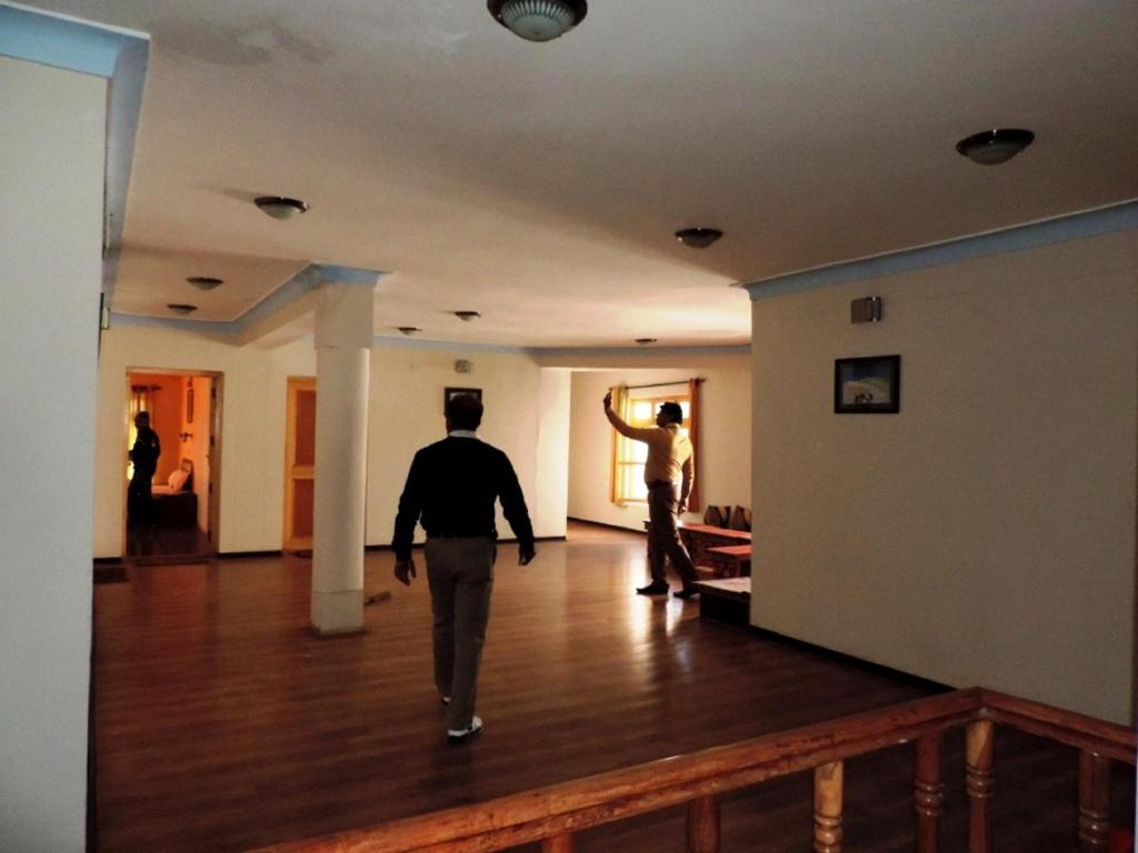 a man walking down a hallway with a man looking out the window at Hotel Ladakh Heaven in Leh