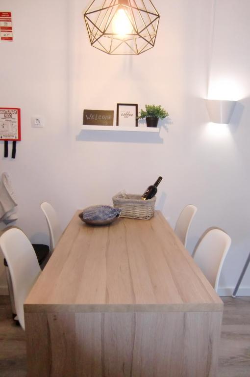 a wooden table with white chairs and a light fixture at The Surf Studio - Ericeira in Ericeira