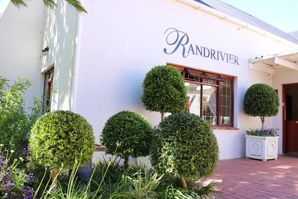 a white building with trees and plants in front of it at Randrivier in Robertson
