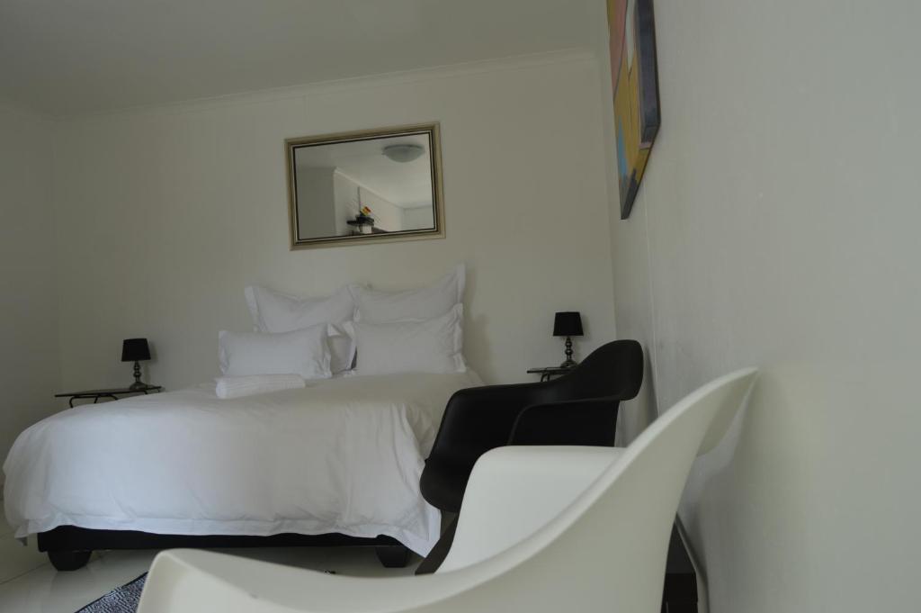 una camera bianca con un letto bianco e una sedia di Niilo's Guesthouse a Rundu