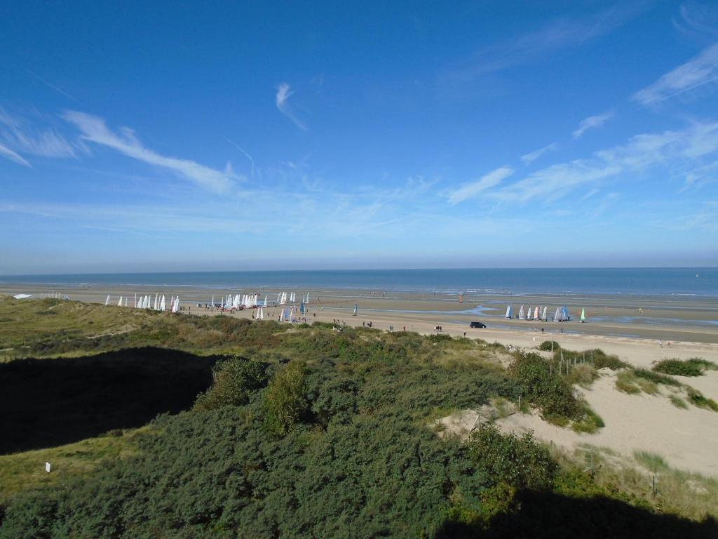 an aerial view of a beach with white umbrellas at Studio Westrand 403 in De Panne
