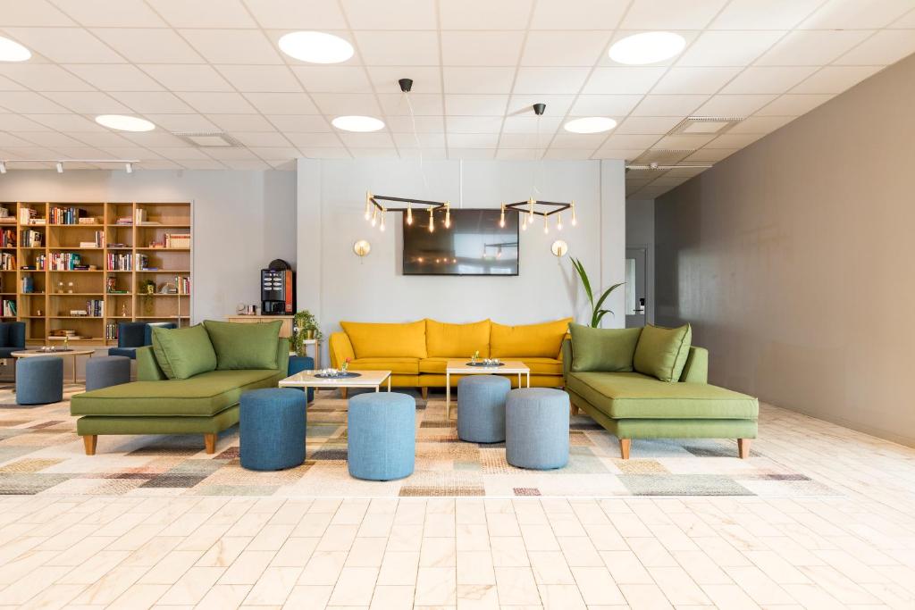 un hall avec des canapés et des tables jaunes et verts dans l'établissement Karlskoga Hotell & Konferens, à Karlskoga